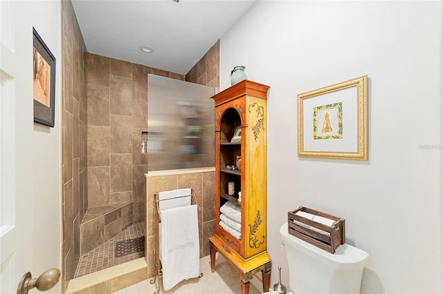 bathroom featuring tiled shower and toilet