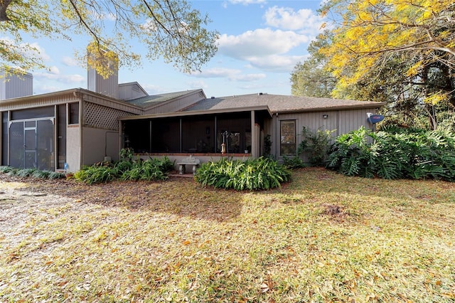 rear view of property with a yard and a sunroom