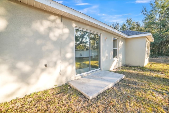 entrance to property with a patio and a lawn