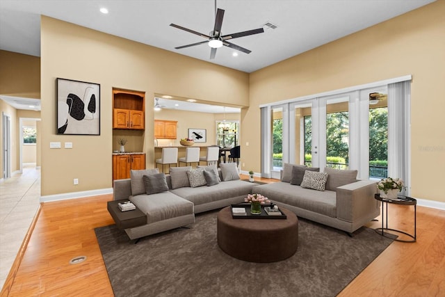 living room featuring light hardwood / wood-style floors, ceiling fan, and a high ceiling