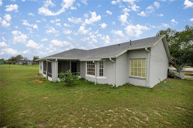 rear view of property with a sunroom, fence, stucco siding, and a yard