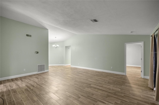 spare room with a chandelier, visible vents, and vaulted ceiling