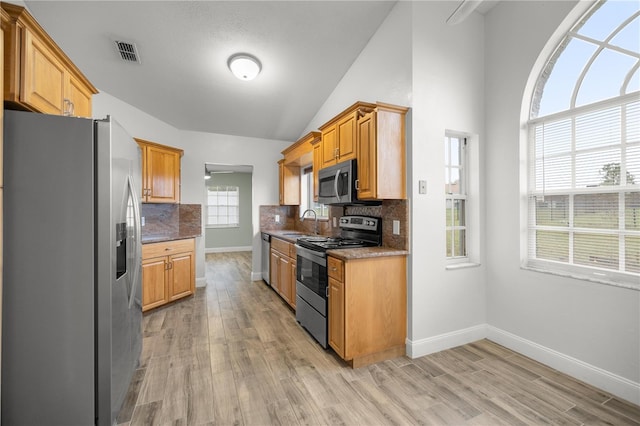 kitchen featuring stainless steel appliances, visible vents, light wood-style flooring, and decorative backsplash