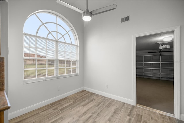 interior space featuring ceiling fan, light wood-type flooring, visible vents, and baseboards