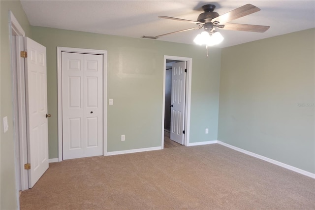 unfurnished bedroom featuring ceiling fan, light colored carpet, and a closet