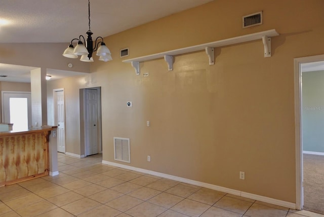 unfurnished room featuring lofted ceiling, light tile patterned floors, and an inviting chandelier