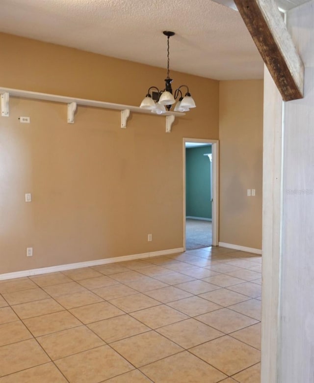 unfurnished room featuring an inviting chandelier, beam ceiling, a textured ceiling, and light tile patterned floors