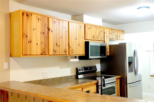 kitchen with a textured ceiling and appliances with stainless steel finishes