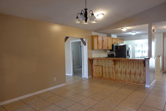 kitchen featuring appliances with stainless steel finishes, light tile patterned flooring, light brown cabinetry, vaulted ceiling, and kitchen peninsula