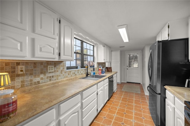 kitchen with decorative backsplash, freestanding refrigerator, white cabinets, a sink, and dishwasher