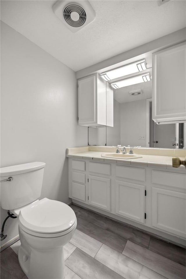 bathroom with vanity, a textured ceiling, and toilet