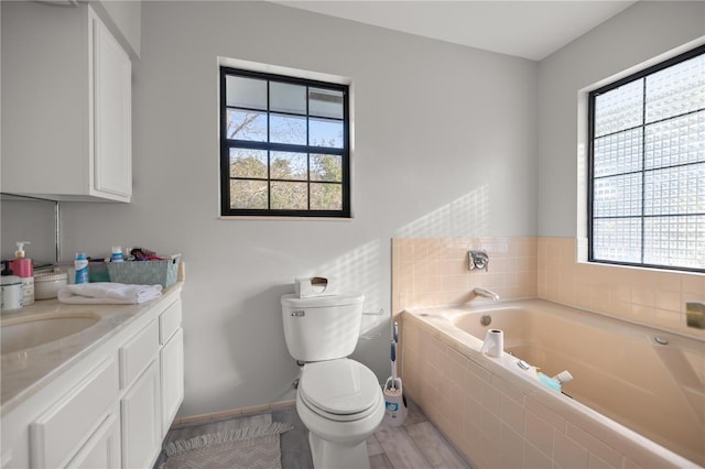 bathroom with vanity, toilet, hardwood / wood-style floors, and tiled tub