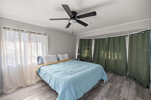 bedroom with hardwood / wood-style flooring, ceiling fan, and ornamental molding