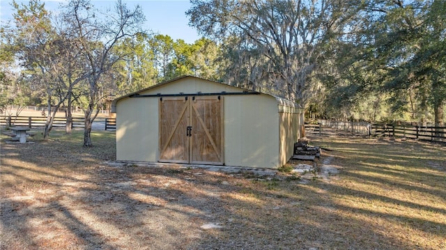 view of outdoor structure featuring fence and an outbuilding