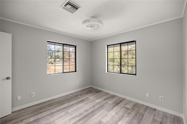 spare room featuring crown molding, light wood-style flooring, visible vents, and baseboards