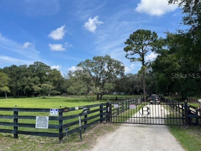 view of gate with a yard and a rural view