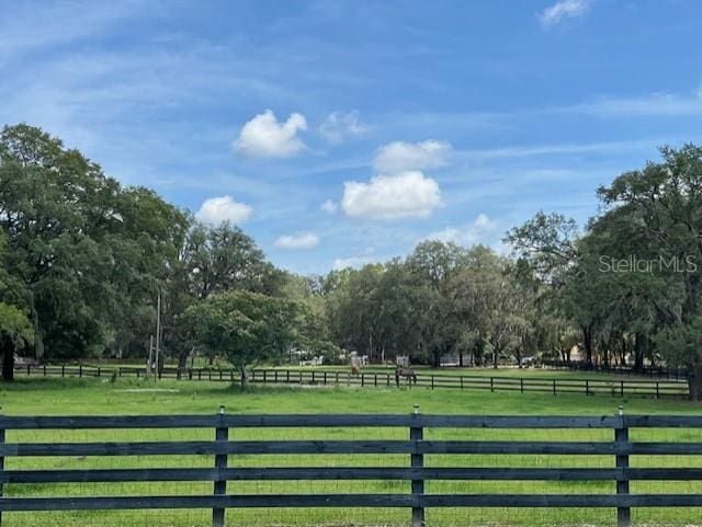 view of gate with a rural view, fence, and a lawn