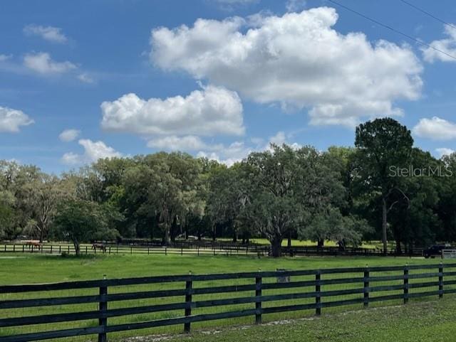 view of gate with a rural view, a yard, and fence