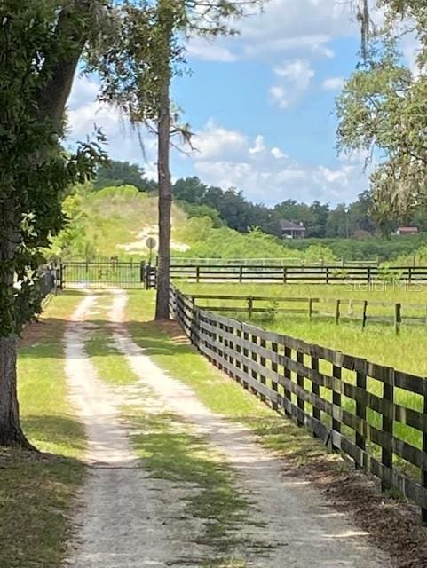 exterior space featuring a rural view, fence, and dirt driveway