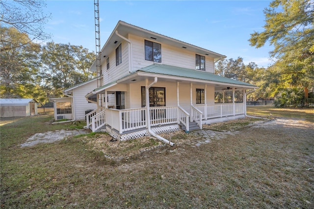 farmhouse inspired home with metal roof, a porch, a front lawn, and fence