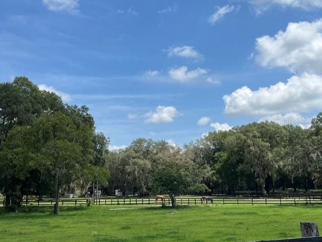 view of home's community featuring a rural view, a lawn, and fence