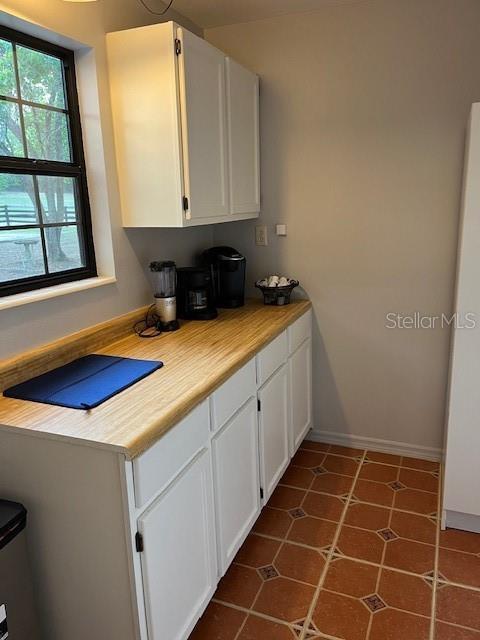 10245 SW 105th St, Ocala, FL 34481 - kitchen with white cabinets, light countertops, baseboards, and dark tile patterned flooring