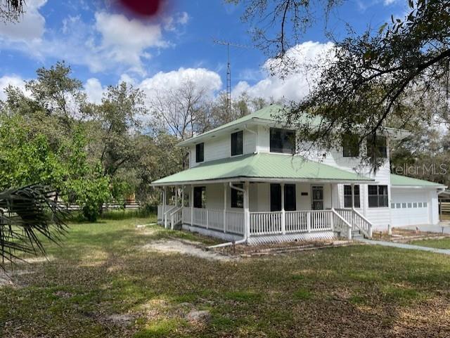 10245 SW 105th St, Ocala, FL 34481 - farmhouse-style home featuring covered porch, a garage, and a front yard