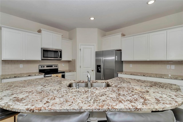 kitchen featuring stainless steel appliances, a breakfast bar, sink, and a kitchen island with sink