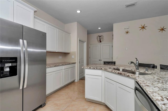 kitchen featuring stainless steel appliances, white cabinetry, light stone countertops, and sink