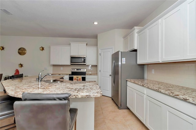 kitchen featuring stainless steel appliances, sink, a center island with sink, and a kitchen breakfast bar