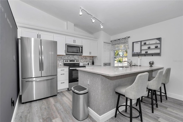 kitchen featuring white cabinetry, a kitchen breakfast bar, kitchen peninsula, and appliances with stainless steel finishes