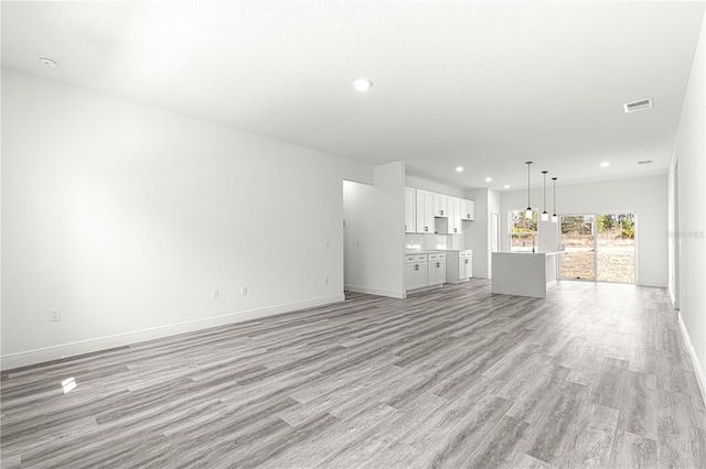 unfurnished living room with a textured ceiling and light hardwood / wood-style flooring