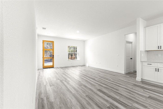 unfurnished living room featuring a textured ceiling and light hardwood / wood-style flooring