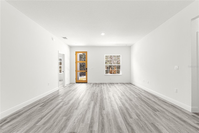 unfurnished living room featuring a textured ceiling and light wood-type flooring