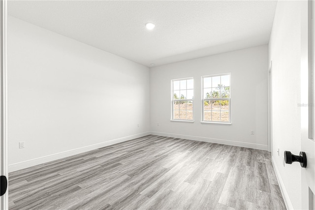 empty room with a textured ceiling and light hardwood / wood-style floors