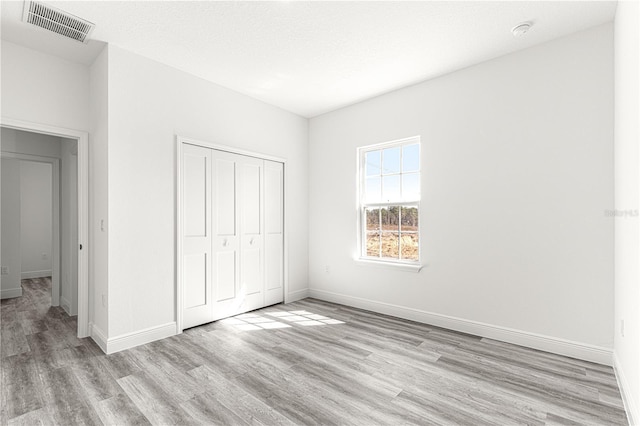 unfurnished bedroom featuring a closet, a textured ceiling, and light hardwood / wood-style flooring