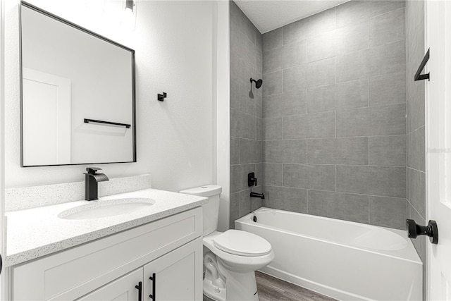 full bathroom featuring tiled shower / bath, wood-type flooring, vanity, and toilet