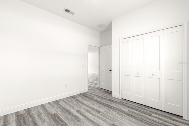 unfurnished bedroom with light wood-type flooring and a closet