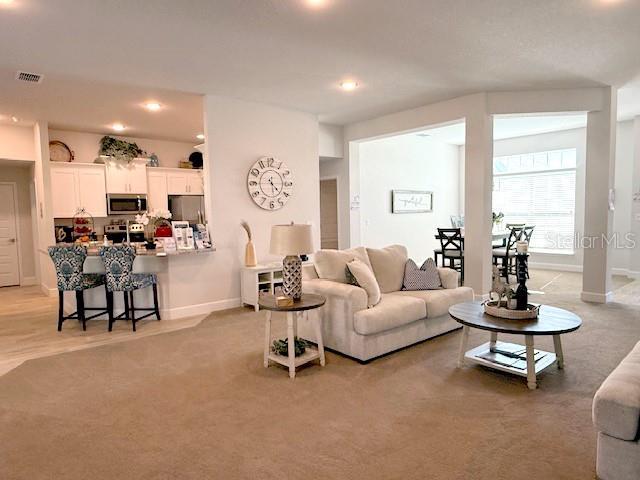 living room with recessed lighting, baseboards, visible vents, and light colored carpet