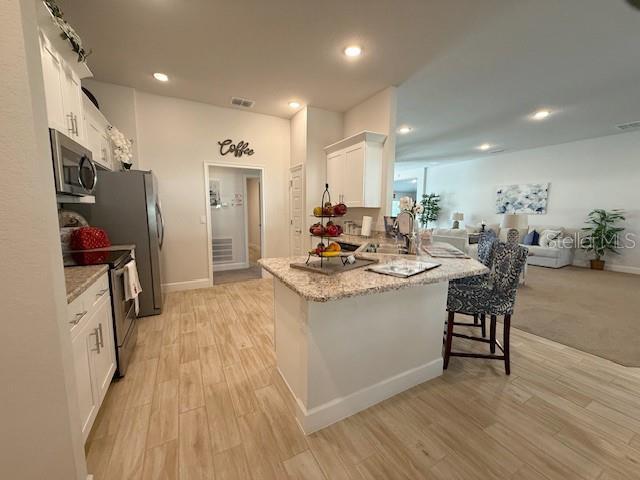 kitchen with appliances with stainless steel finishes, white cabinets, a sink, and light wood-style flooring