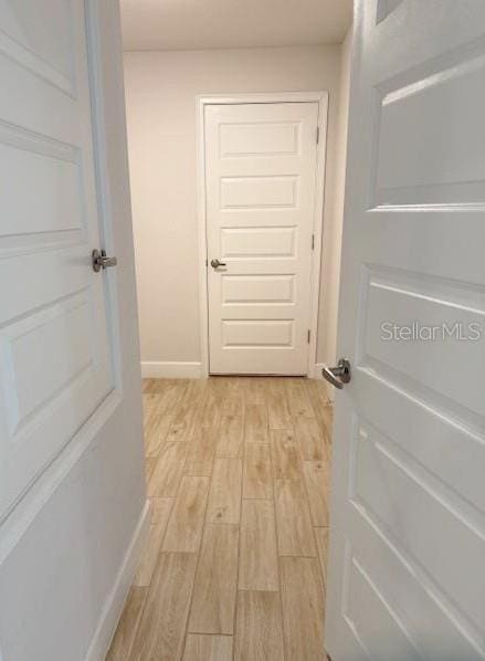 hall with light wood-style flooring and baseboards