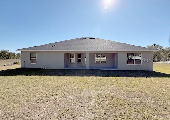 back of property with a patio area, a lawn, and stucco siding