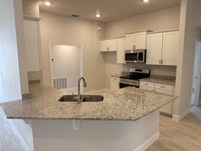 7 NW 45th Loop, Ocala, FL 34470 - kitchen featuring stainless steel appliances, a sink, a peninsula, light stone counters, and recessed lighting