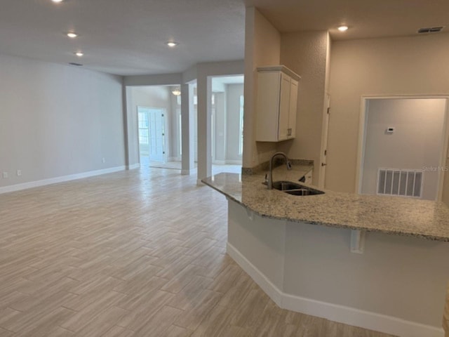 7 NW 45th Loop, Ocala, FL 34470 - kitchen featuring a sink, light wood finished floors, a kitchen breakfast bar, a peninsula, and baseboards