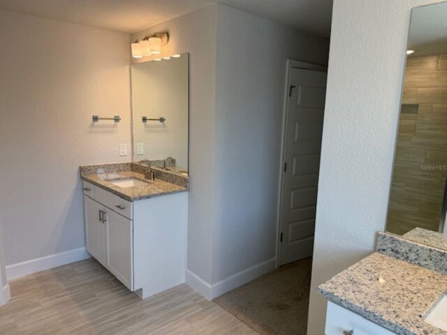 7 NW 45th Loop, Ocala, FL 34470 - full bath with two vanities, baseboards, wood finished floors, and tiled shower