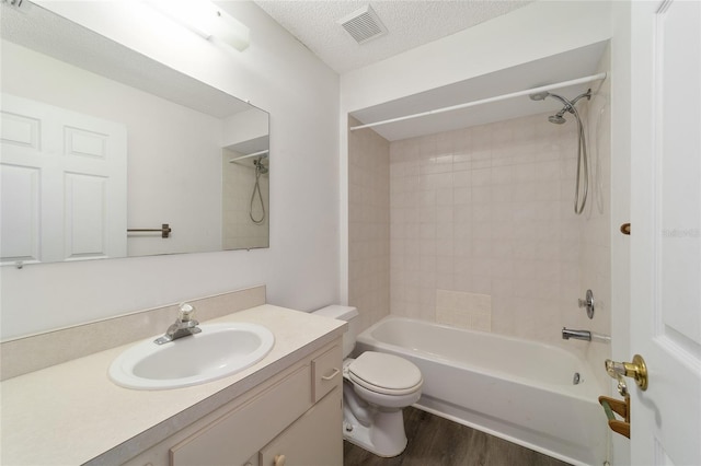 full bathroom with toilet, tiled shower / bath, wood-type flooring, a textured ceiling, and vanity