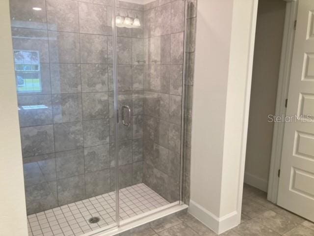 bathroom with an enclosed shower and tile patterned floors