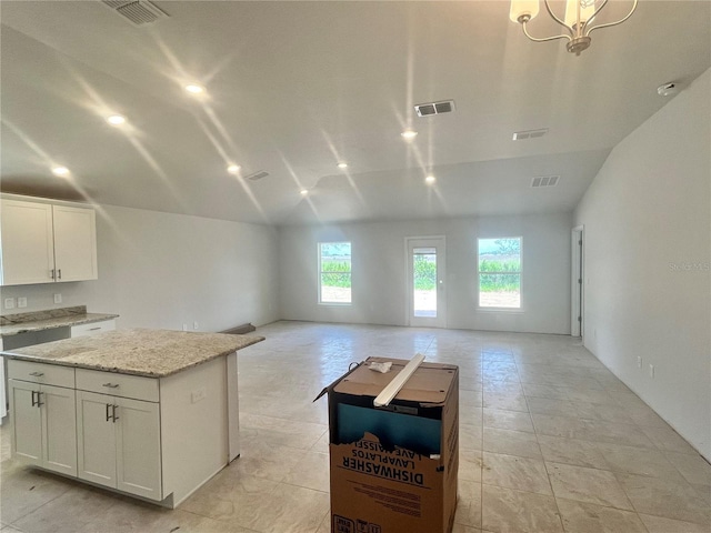 4373 SW 90th Pl, Ocala, FL 34476 - kitchen featuring a center island, lofted ceiling, open floor plan, white cabinetry, and light stone countertops
