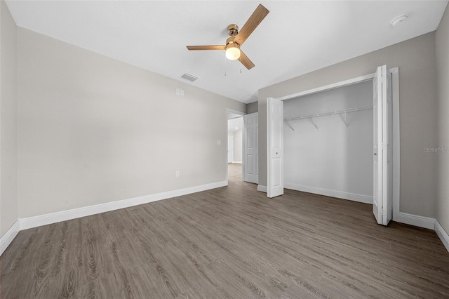 unfurnished bedroom with ceiling fan, dark hardwood / wood-style flooring, and a closet