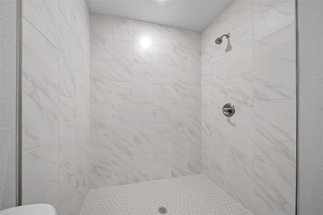 bathroom with toilet and a tile shower